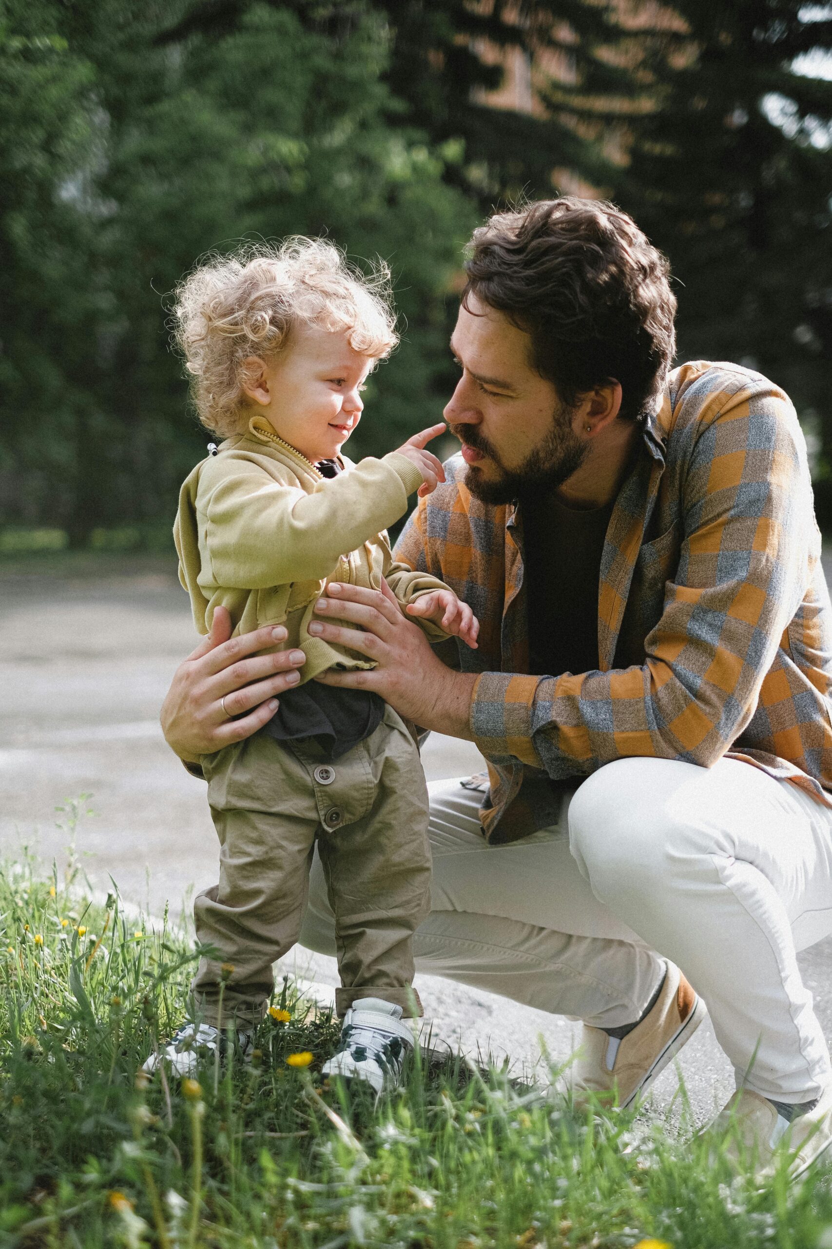 A father and his young son share a playful moment outdoors, emphasizing family and bonding.